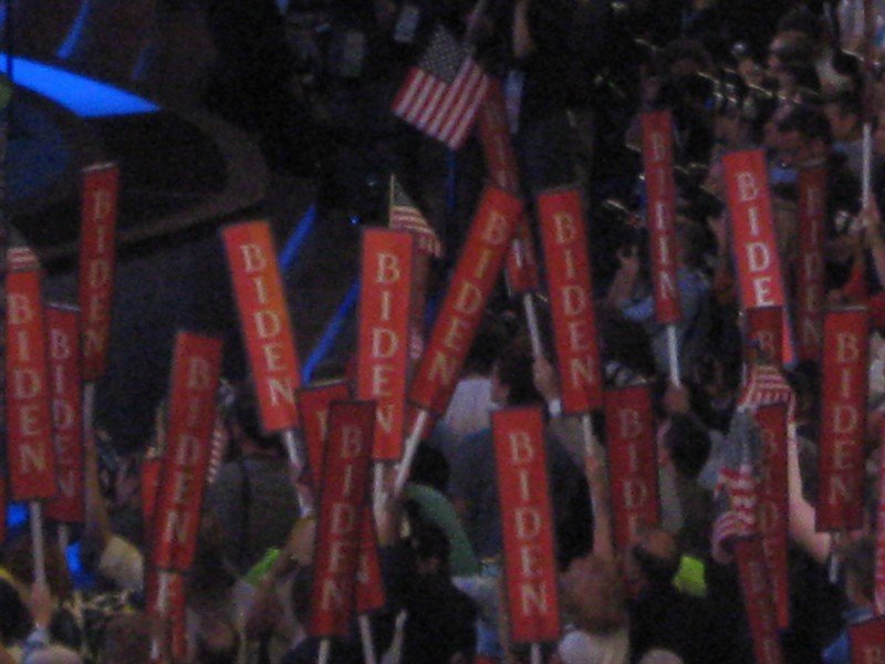 Crowd of delegates holding red “Biden” signs and American flags