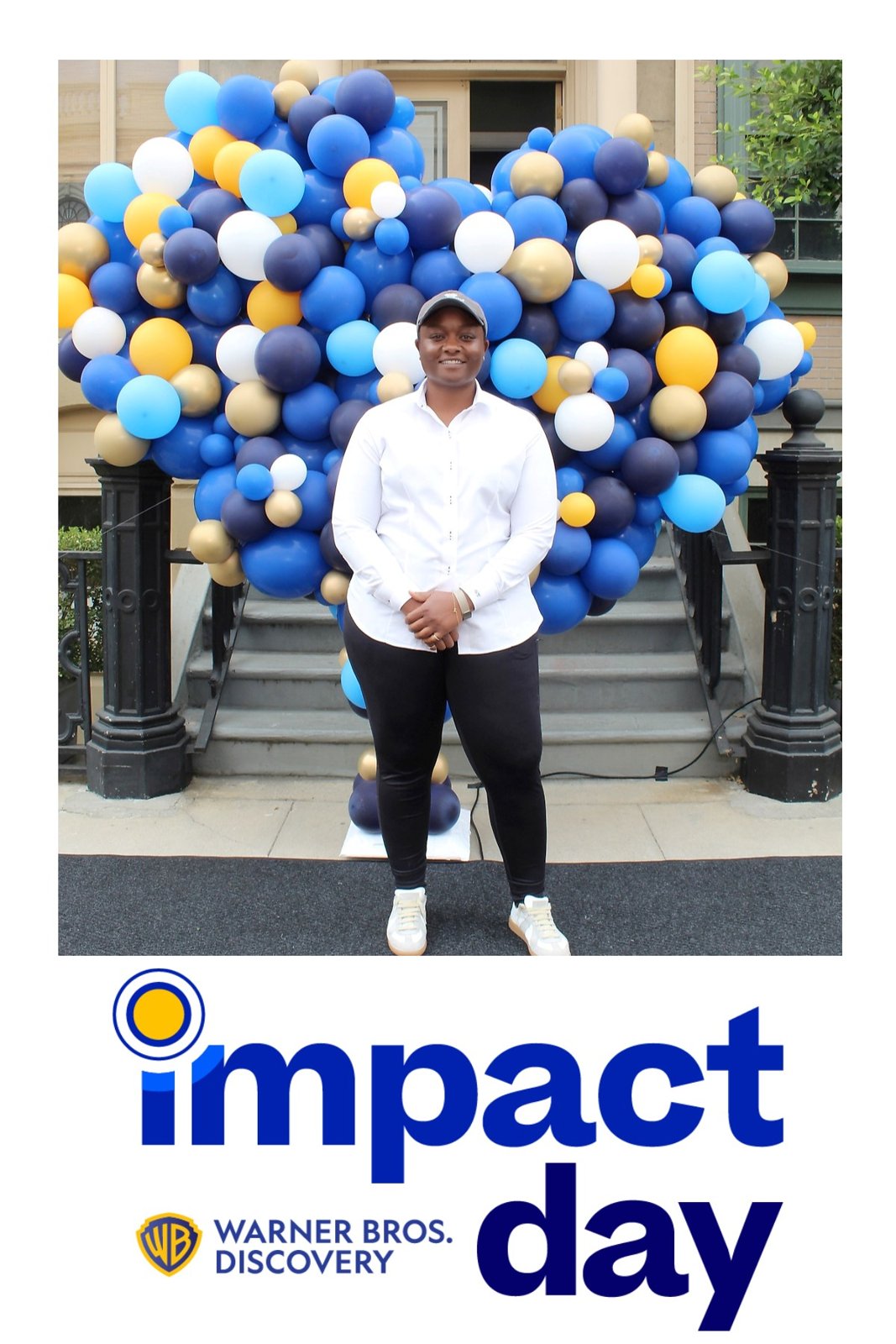 Sajdah standing in front of a balloon installation at a Warner Bros. Discovery Impact Day event